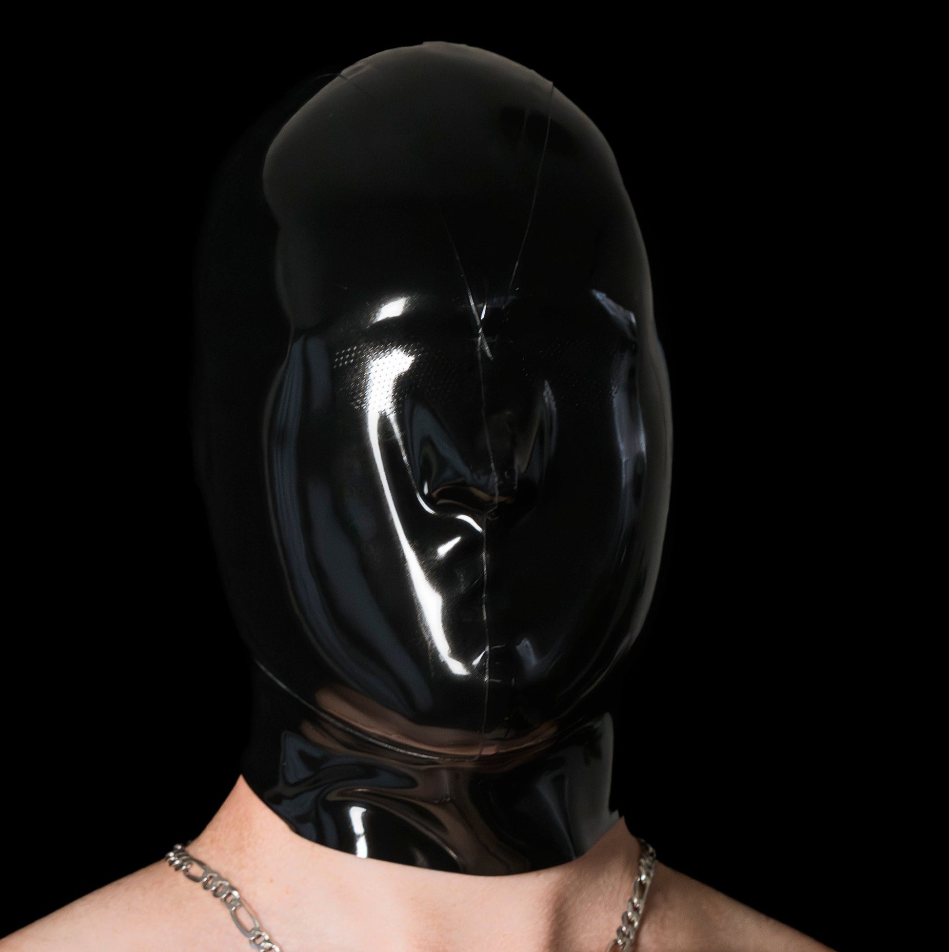 Person wearing a black latex hood with a dark background