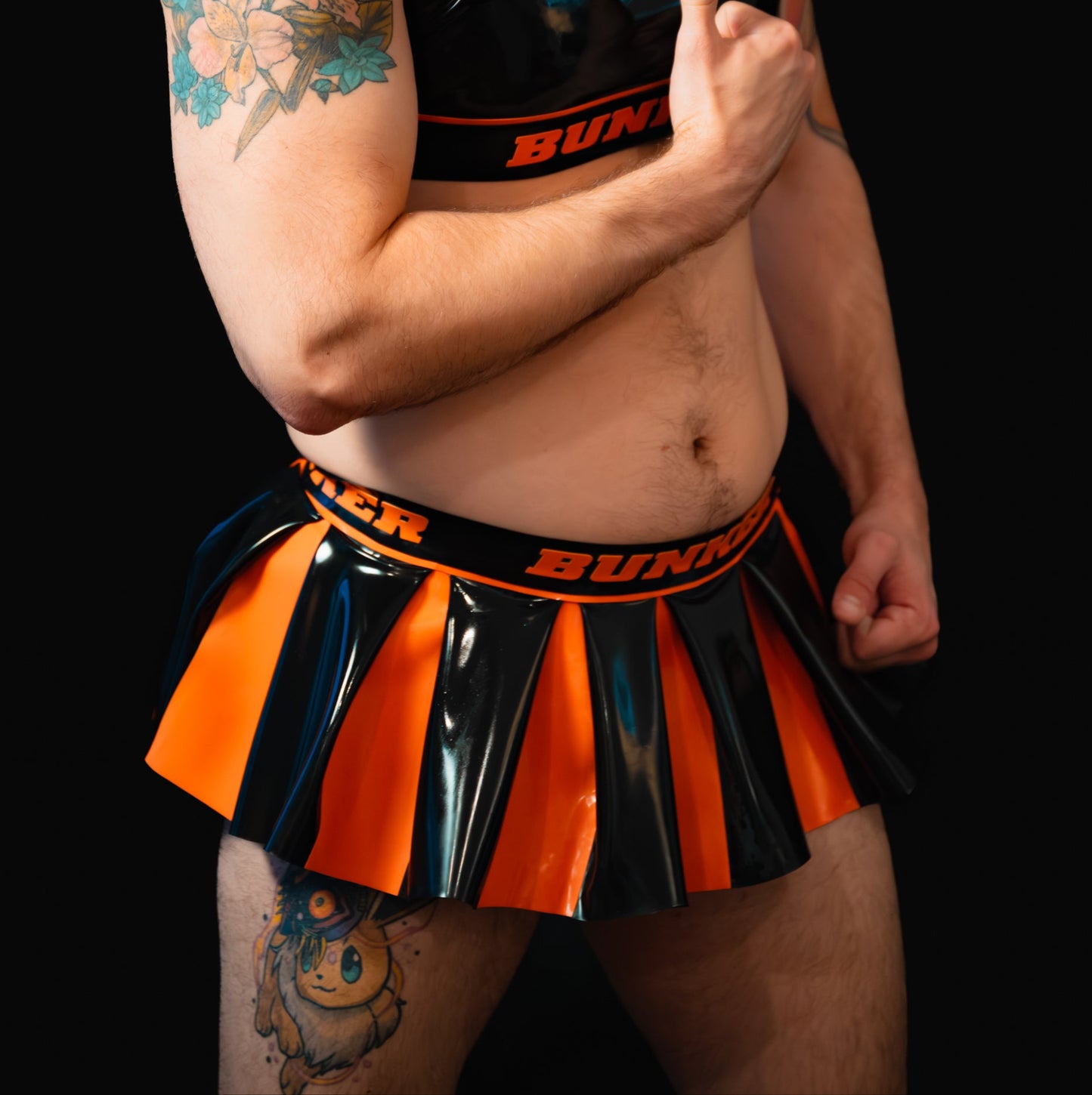 Man wearing a black and orange outfit with 'BUNKER' branding on a black background