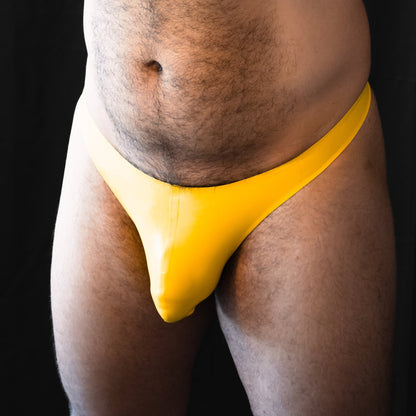 A person wearing a yellow thong that has a snug fit, showing the design and color of the underwear.